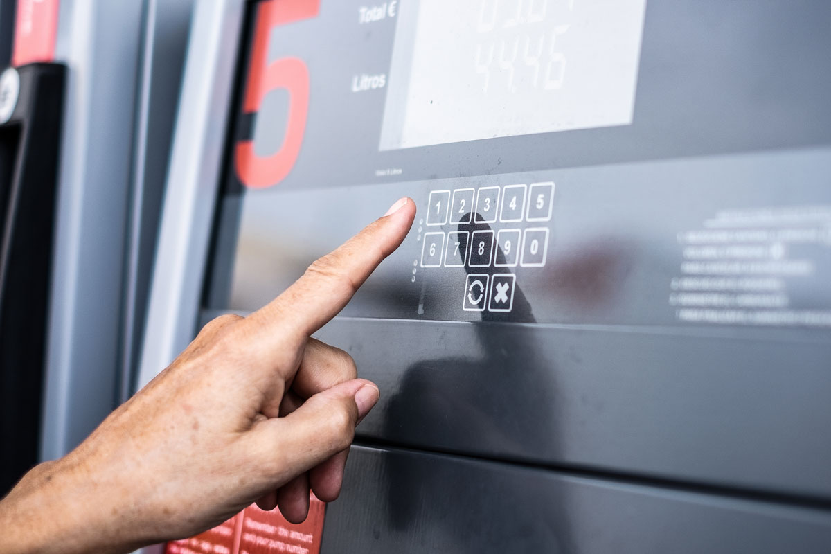Hand tippt auf Folientastatur einer Zapfsäule mit Designfolie, klare Zahlenfelder und Display