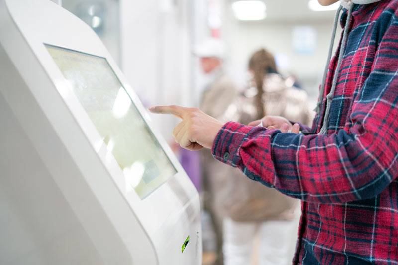 Person nutzt kapazitiven Touchscreen an einem digitalen Terminal