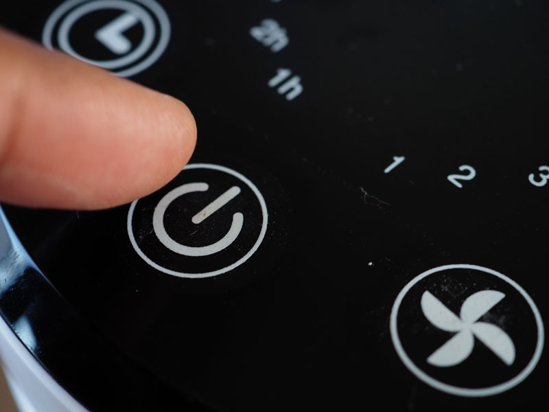 Finger drückt Ein- und Ausschalter auf einem Touch-Bedienfeld mit Designfolie