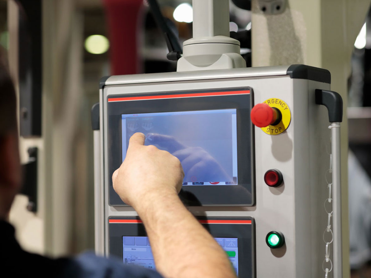 HMI Touchscreen mit Not-Aus-Schalter in industrieller Produktionsumgebung